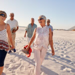 Group Of Senior Friends Walking Along Sandy Beach On Summer Group Vacation Group Of Senior Friends Walking Along Sandy Beach On Summer Group Vacation